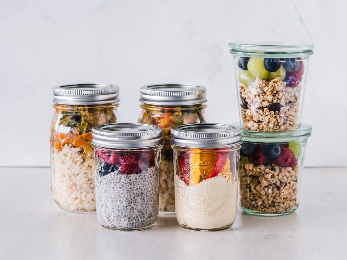 mason jars filled with oatmeal, berries, and granola