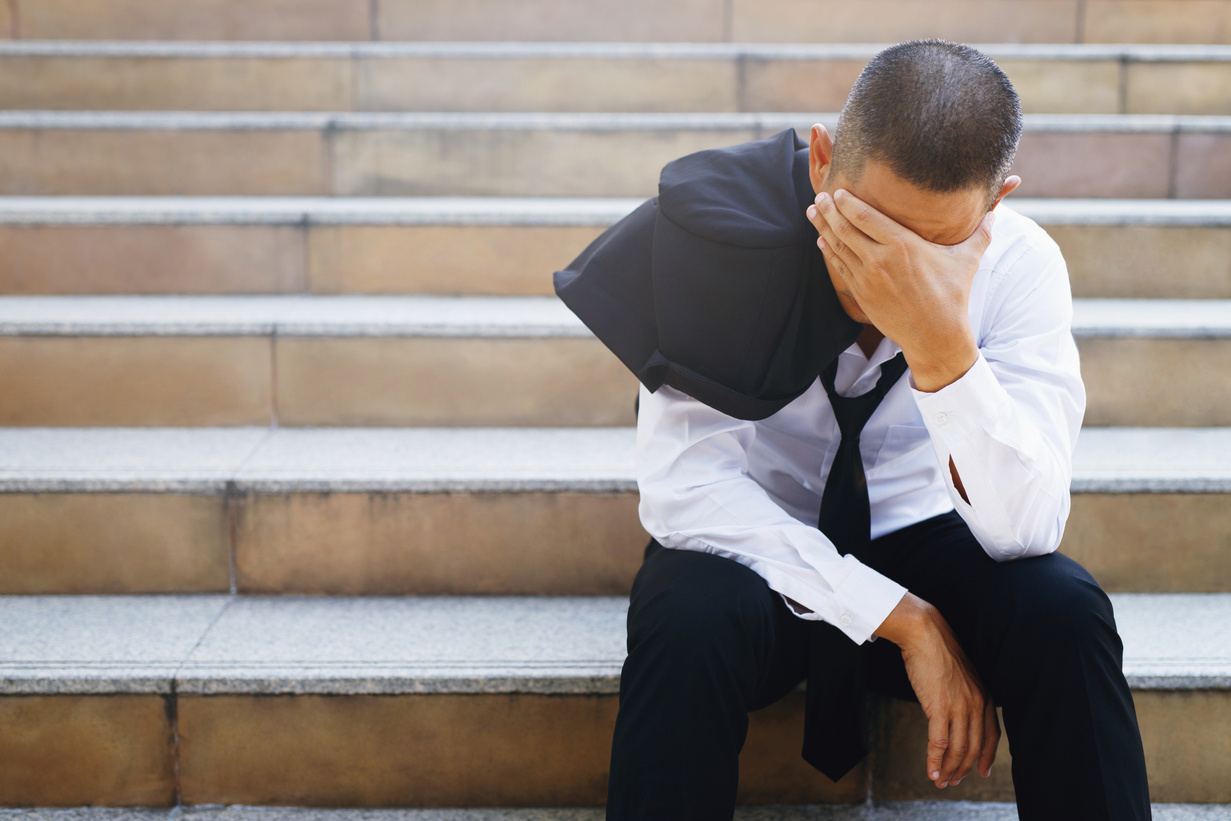 Stressed Man Sitting on the Stairs with Hands on Head 